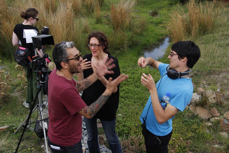 Group of film professionals using sign language against a grassy background